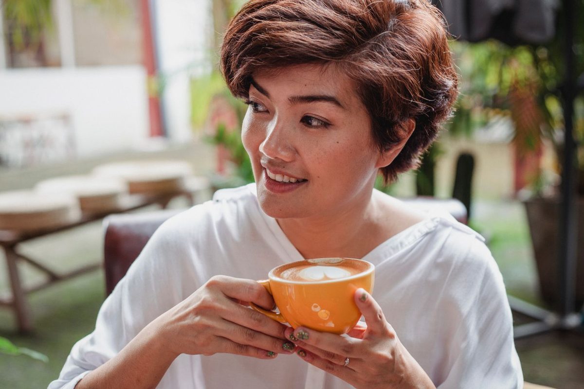 コーヒーを手にほっとひと息つく女性
