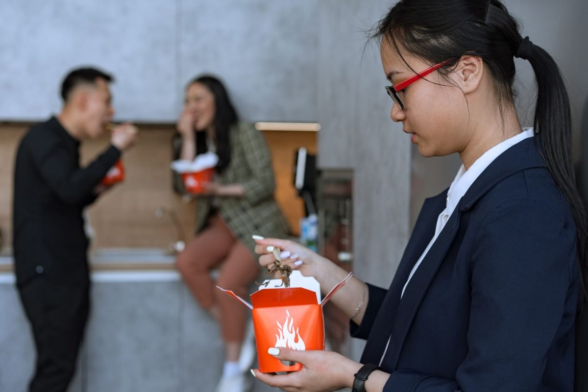 同僚が食事する中、弁当を手にする女性